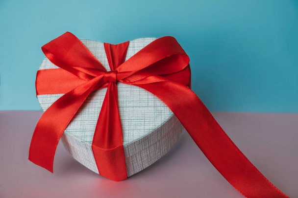 Caja de regalo blanca con lazo rojo sobre fondo colorido. Regalo de vacaciones para su ser querido. Regalo de San Valentín - Foto, Imagen