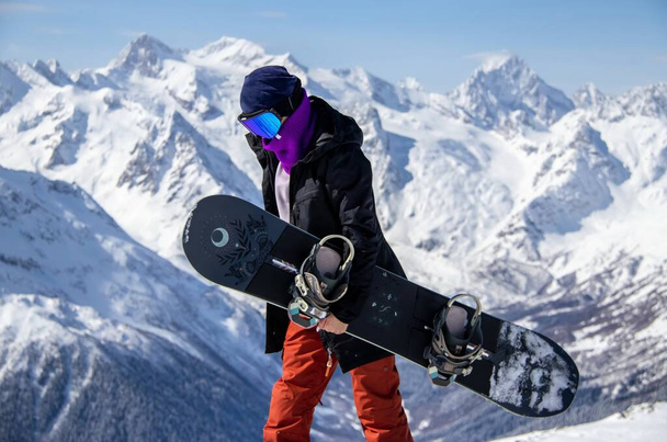 Portrait of a girl with snowboard on top of a snowy mountain. - Фото, изображение