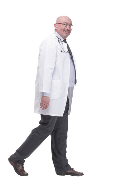 confident mature doctor in a white coat striding forward . - Fotoğraf, Görsel