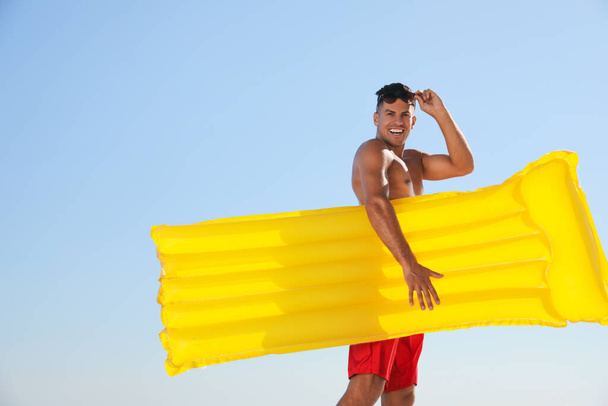 Man with yellow inflatable mattress against blue sky - Zdjęcie, obraz