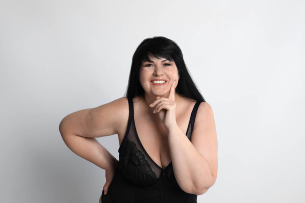 Beautiful overweight woman in black underwear on light background. Plus-size model - Foto, Bild