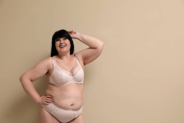 Beautiful overweight woman in underwear on beige background, space for text. Plus-size model - Foto, Imagem