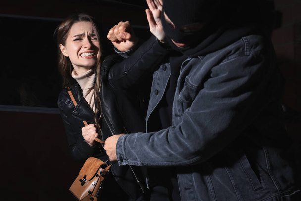 Woman fighting with thief while he trying to steal her bag outdoors at night. Self defense concept - Foto, Imagen