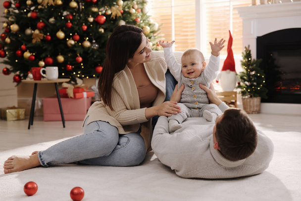 Happy family with cute baby on floor in room decorated for Christmas - Fotó, kép