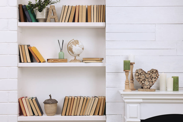 Collection of books and decor elements on shelves indoors - 写真・画像