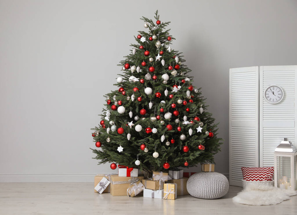 Beautifully decorated Christmas tree and many gift boxes in room, space for text - Foto, imagen