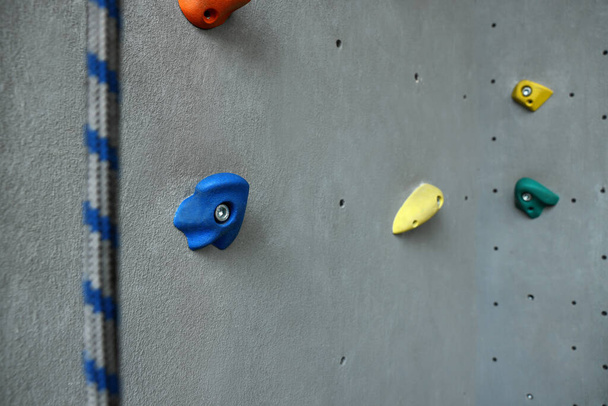 Colorful climbing wall with holds and rope. Extreme sport - Fotografie, Obrázek