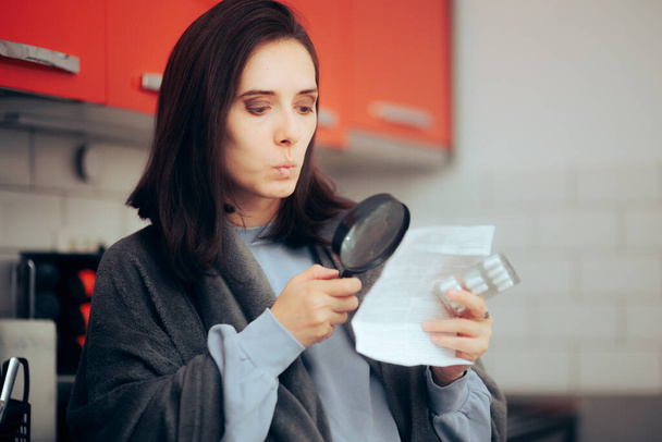 Woman Using a Magnifier Glass to Read Medicine Leaflet of Pills - Photo, image