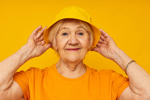 Photo of retired old lady in yellow t-shirts hat posing isolated background - Фото, зображення