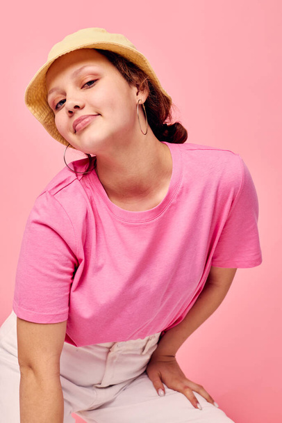 Young woman fashion clothes hat pink t-shirt decoration posing pink background - Foto, imagen