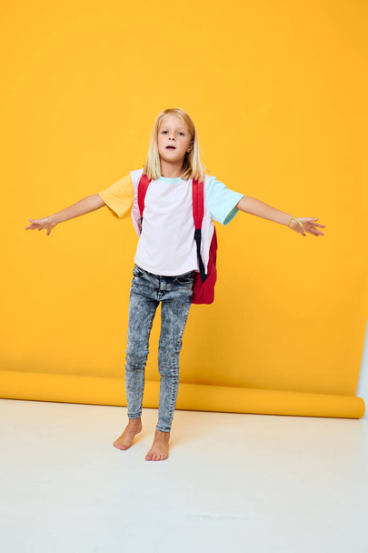 mignonne écolière avec un sac à dos rouge fond de couleur jaune - Photo, image