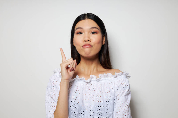cute asian woman in white shirt holds her hand near her face - Zdjęcie, obraz
