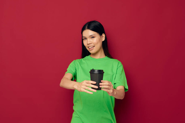 woman with Asian appearance in a green t-shirt a glass of drink fun isolated background unaltered - Foto, Imagem