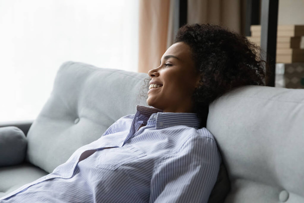 Smiling peaceful young african woman resting on couch. - Foto, Imagen