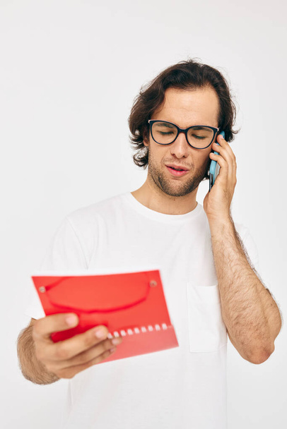 Attractive man in a white T-shirt red notepad Lifestyle unaltered - 写真・画像
