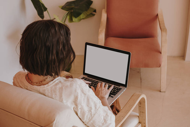 rear view of woman working on laptop with blank screen - Photo, Image