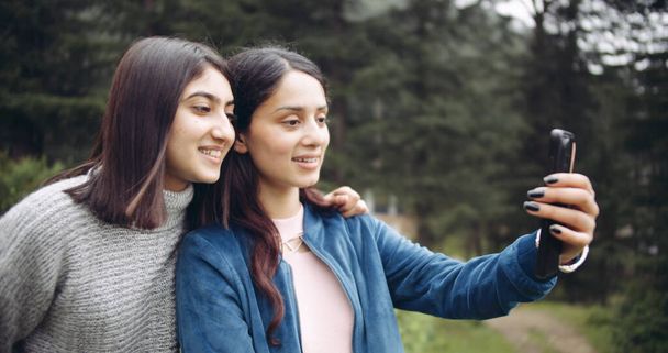two young women taking selfie with smartphone in park - Fotoğraf, Görsel