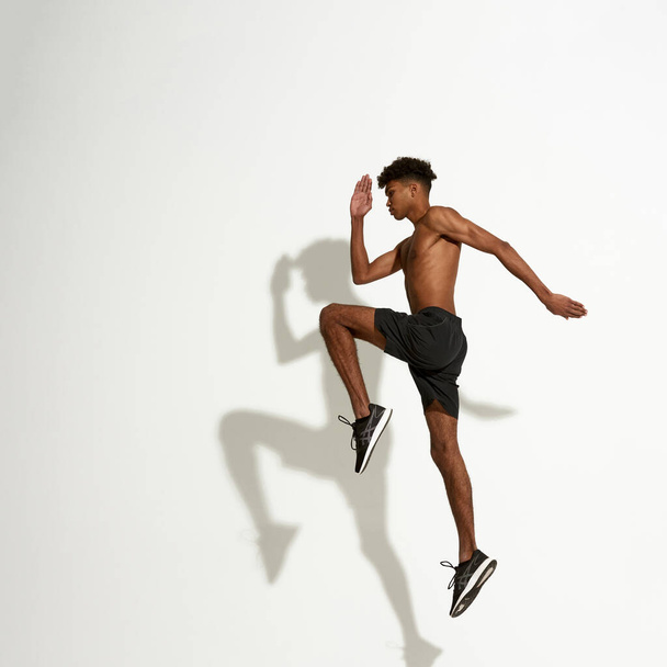 Side view of young african sportsman jumping - Photo, image