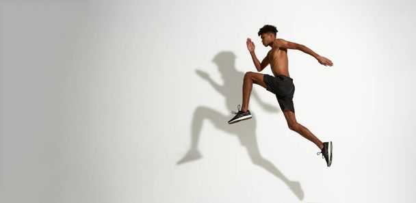 Side view of serious sportsman running and jumping - Φωτογραφία, εικόνα