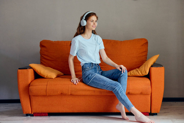 cheerful woman sitting on the couch at home listening to music on headphones technologies - Fotoğraf, Görsel