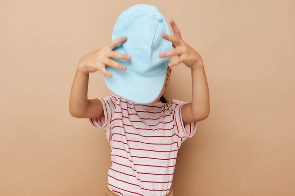 klein meisje in blauw caps gestreepte t-shirt emoties Lifestyle ongewijzigd - Foto, afbeelding