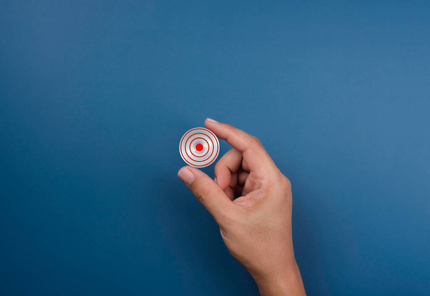 Modern small red target icon symbol in hand on blue. Small business, goal and success concept. Concept of objective attainment and business niche market and specializing in a smaller opportunity. - Foto, Imagen
