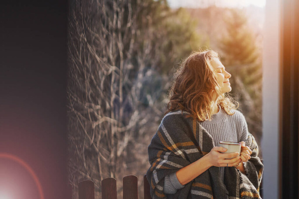 Happy cheerful beautiful curly young woman enjoying morning coffee and mountain view on the terrace of a country house - Foto, imagen
