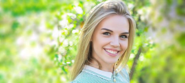 Spring woman face for banner. Cute young spring woman girl with blossom background. Smiling summer female at park. Optimistic mood. Beauty young woman enjoying nature in spring garden. - Φωτογραφία, εικόνα