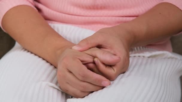 Young woman sitting on sofa and feeling thumb pain(De Quervain syndrome) and she massage her hand at home. Hand injury or inflammation of chronic arthritis. Health and medical concepts. - Кадры, видео