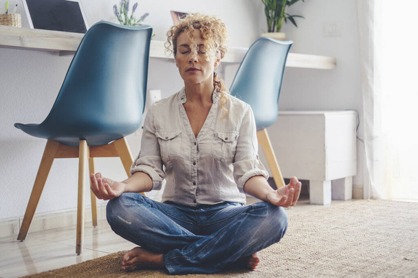 woman sitting in asana and meditating at home - Foto, Imagem