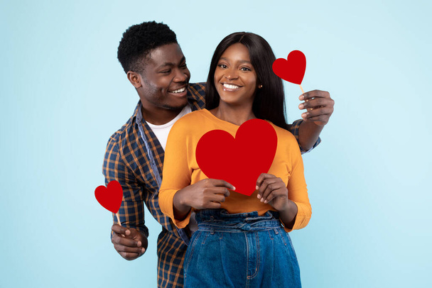 Young Romantic Black Couple Posing And Holding Red Paper Hearts - Foto, Imagen