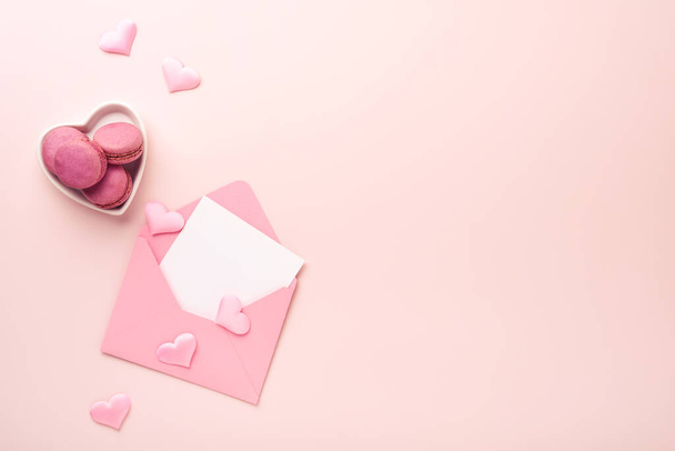 Valentines Day card. Pink empty envelope with blank white note mockup inside, macaron macaroon cookie and heart shaped coffee cup on pink background. 8 March, Womens Mothers Valentines Day, Birthday - Fotoğraf, Görsel