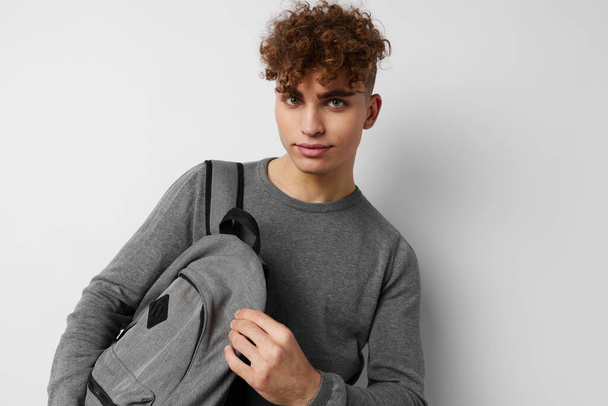 handsome young man in a gray sweater backpack fashion isolated background - Foto, Imagem