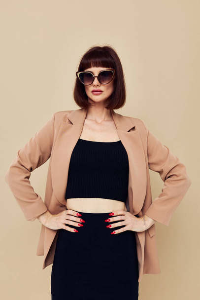 photo pretty woman in a beige jacket elegant style sunglasses isolated background - Foto, afbeelding