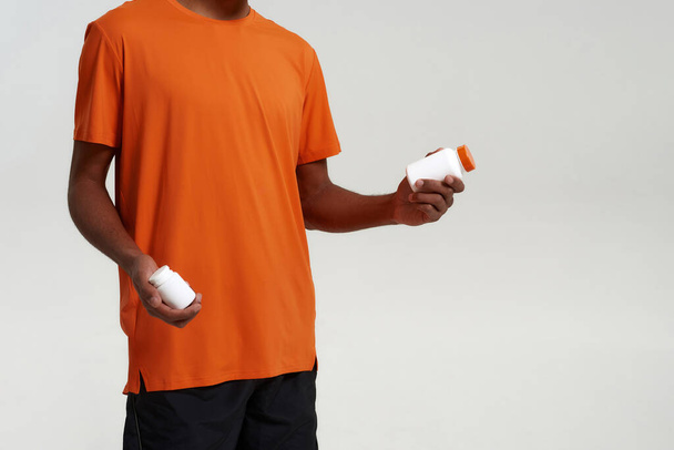 Partial of black man hold jars with medical pills - Foto, Imagen