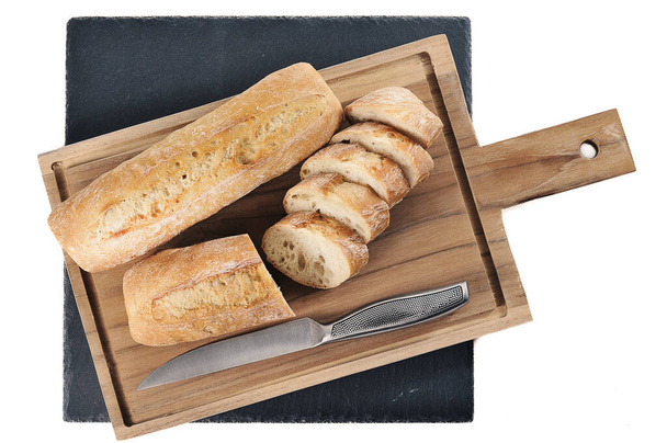small French baguette on a wooden board and a knife - top view flat lay - Fotografie, Obrázek