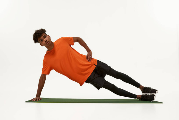 Black sportsman doing side plank on fitness mat - Foto, Imagem
