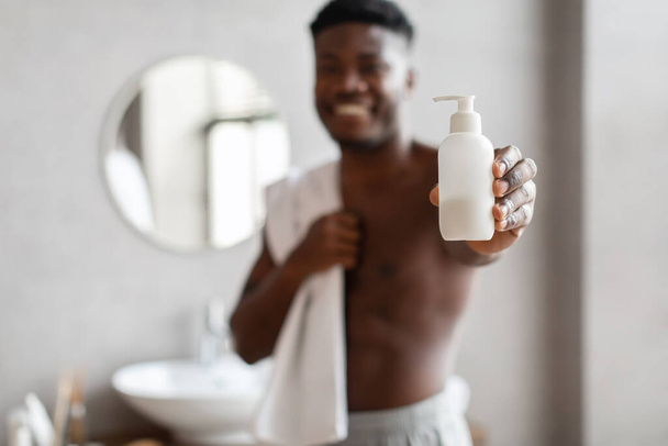 Unrecognizable African American Man Showing Liquid Soap Bottle In Bathroom - Foto, imagen