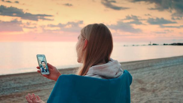 海岸でスマホでビデオ通話をする女 - 写真・画像