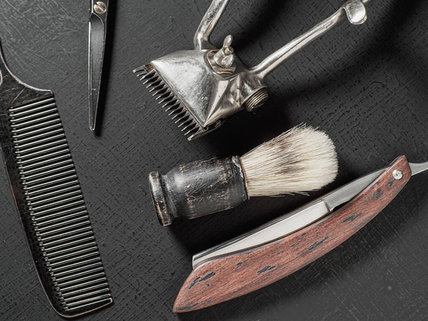 vintage barber tools dangerous razor hairdressing scissors old manual clipper comb shaving brush. on a black - Fotografie, Obrázek