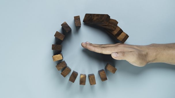 Top view and flat lay design of Businessman use gesture to stop wooden domino circle falling for insurance assurance and risk management concept. - Fotoğraf, Görsel