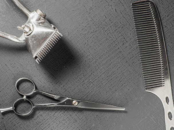 Vintage hairdressing tools. Barber scissors old manual hair clipper. On a black surface - Foto, afbeelding
