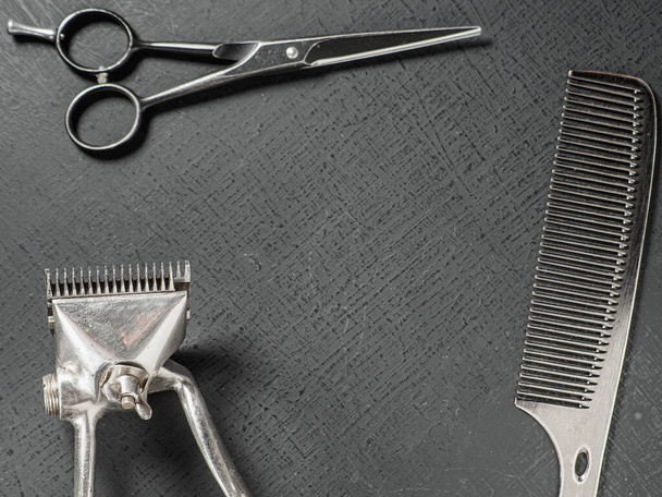 Vintage hairdressing tools. Barber scissors old manual hair clipper. On a black surface - Foto, imagen