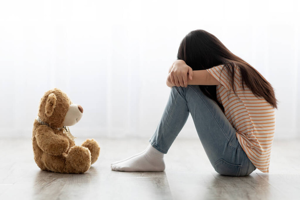 Triste niña de pelo largo sentada con juguete, llorando - Foto, Imagen