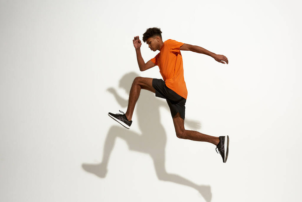Side view of black serious sportsman run and jump - Fotografie, Obrázek