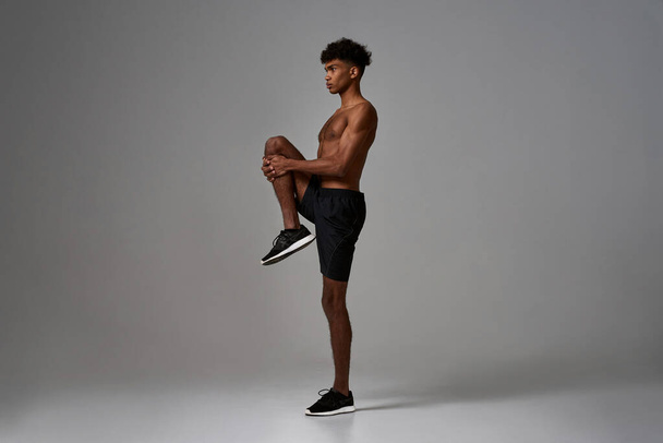 Side view of black serious sportsman stretch leg - Fotó, kép