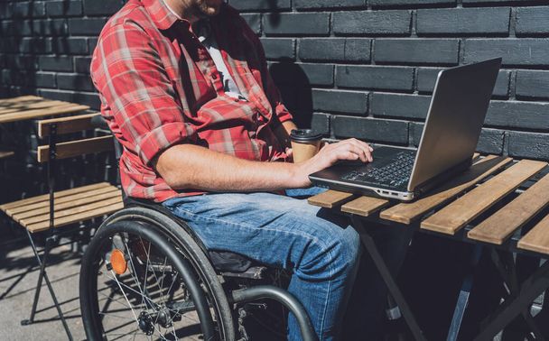 Фрілансер з фізичною вадою, який використовує інвалідне крісло, що працює у вуличному кафе
 - Фото, зображення