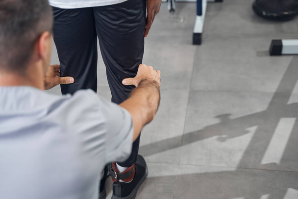 Experienced physiotherapist examining legs of man by touch - Valokuva, kuva