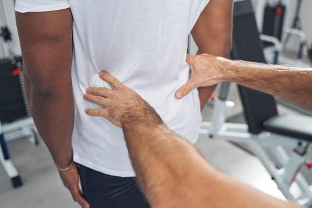Experienced physical therapist palpating patient lower back - Photo, image