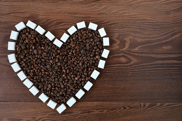 heart made of coffee beans and pieces of white sugar on a wooden surface. Flat layout with top view. Close-up. Copy space - Foto, Imagem